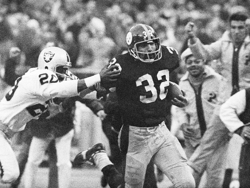 Pittsburgh Steelers' Franco Harris (32) eludes a tackle by Oakland Raiders' Jimmy Warren as he runs 42-yards for a touchdown after catching a deflected pass during an AFC Divisional NFL football playoff game in Pittsburgh on Dec. 23, 1972.