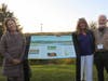 From left, State Representative Teresa Tanzi, State Representative Carol Hagan McEntee and Richard Grant, President of Narrow River Preservation Association, at the unveiling of an informational panel honoring the little red shack on Sedge Island.