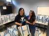 (L) Wendy Ng of Malden YMCA and (R) Andrea Munoz of Tufts Health Plan with 150 filled grocery bags for local families. 