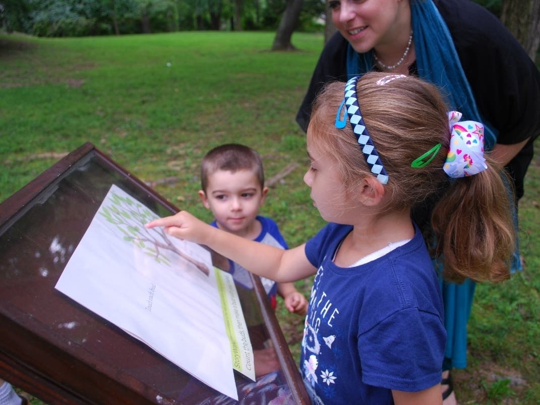 Joy Harrington of Vienna parks and recreation checks out StoryWalk with her children David and Isabella.