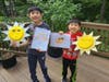 Third place winner Zach (left) and second-grader Logan show their art for the Ipsun Sunny Summer Art Contest.