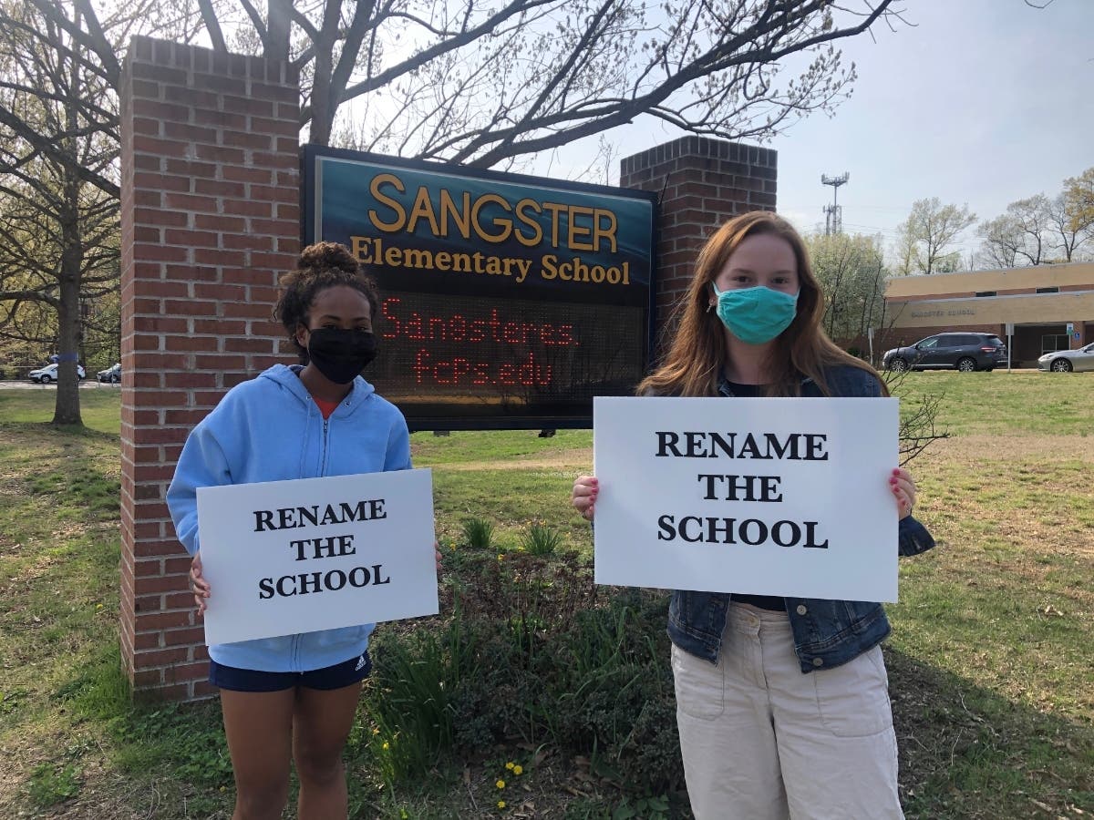 Alumnae Sophia Wallace (left) and Caley Nee (right) set up a "Change the Name" sign outside Sangster Elementary School.