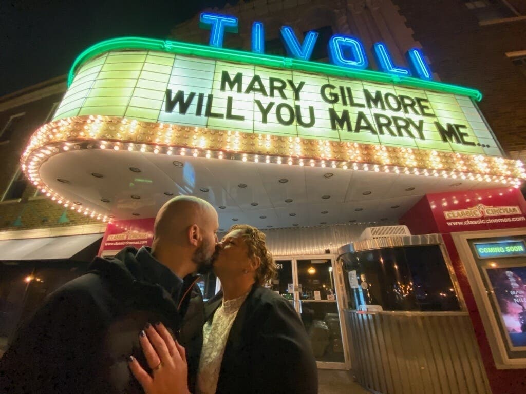Stephan Santoro and Mary Gilmore kiss in front of the Tivoli Theatre marquee after their engagement. 