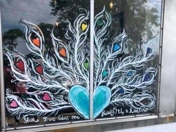 Pride-inspired art decorates the window of a storefront in Downers Grove. 