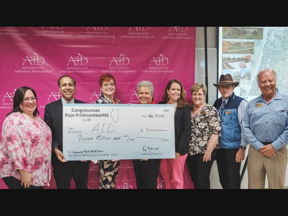 Congressman Krishnamoorthi presents a check commemorating the federal funding he secured to representatives of the Association for Individual Development.