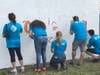 AT&T employees paint a huge school logo mural on the backside of Kelsey L. Pharr Elementary