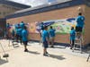 AT&T employee volunteers paint a bright mural at the front entrance of Kelsey L. Pharr Elementary School in Miami