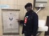 Bashir Muhammad Akinyele standing outside his classroom at door at Weequachic High School in Newark, NJ pointing to a poster of the 42 Principles of Ma’at of ancient Kemet (Egypt). 