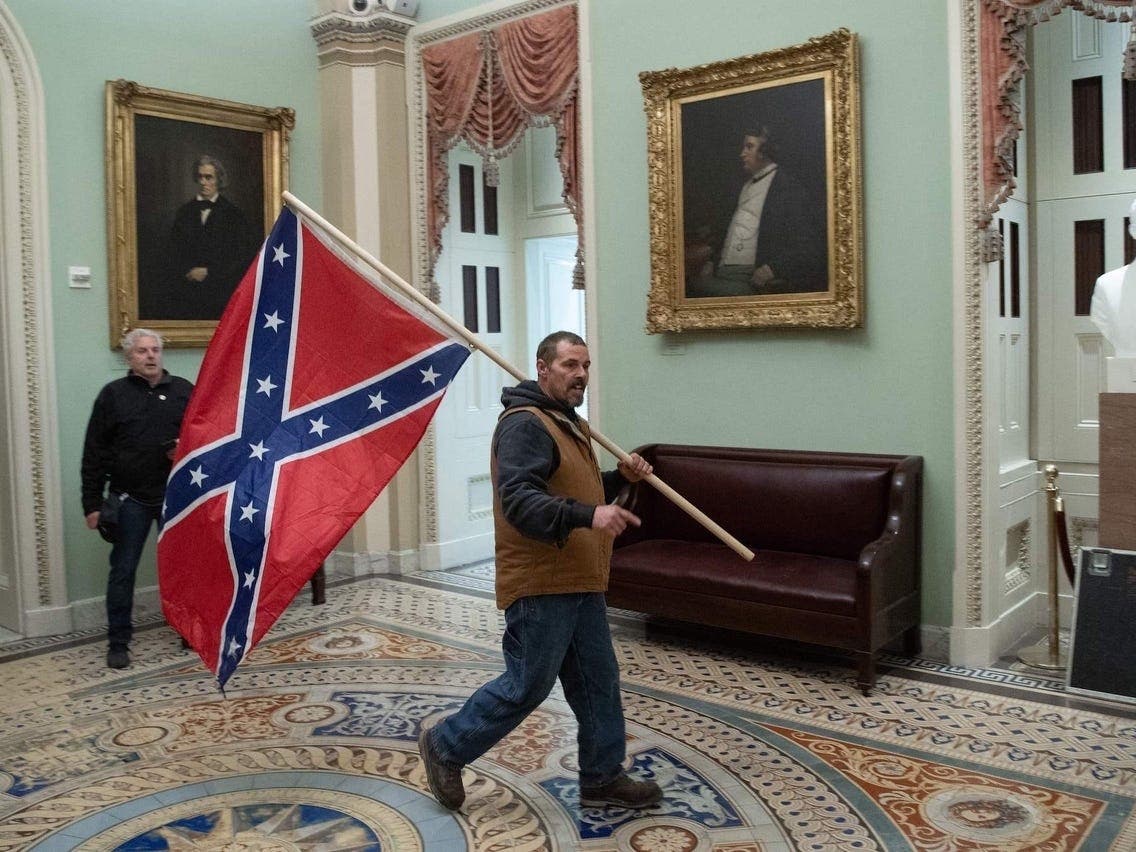 A Trump Supporter walking with the Confederate flag during the staged coup and insurrection of the US in 2021