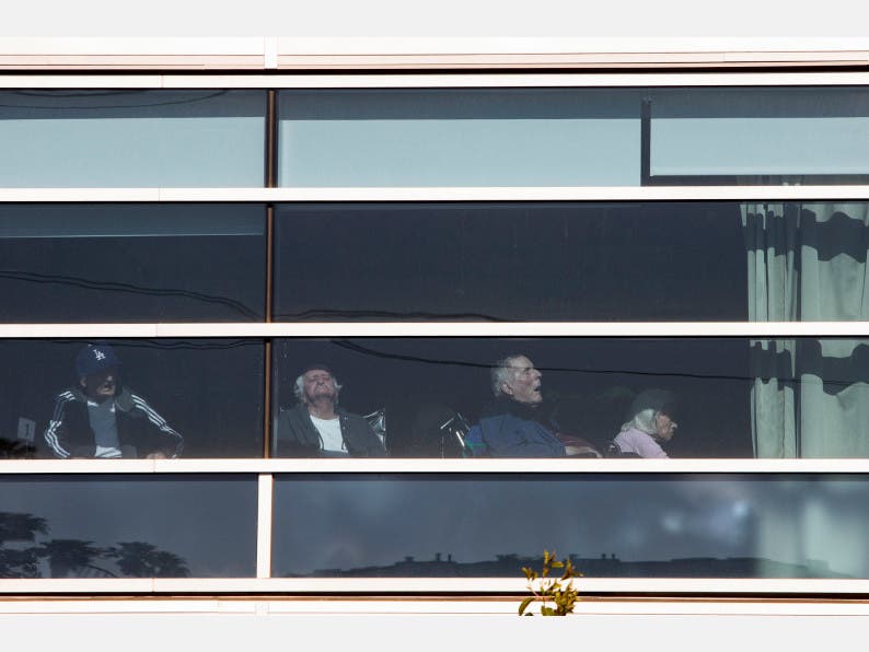 Seniors are seen through the window at Grancell Village of the Los Angeles Jewish Home for the Aging in Reseda on April 11. California officials have said they may require nursing homes to accept COVID-19 patients discharged from hospitals.