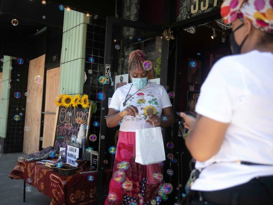 Lilly Ayers places a stick of sage in a bag while serving a customer at her store Queen Hippie Gypsy in downtown Oakland. All of the small businesses on Ayers’ block were damaged during California protests over the killing of George Floyd.