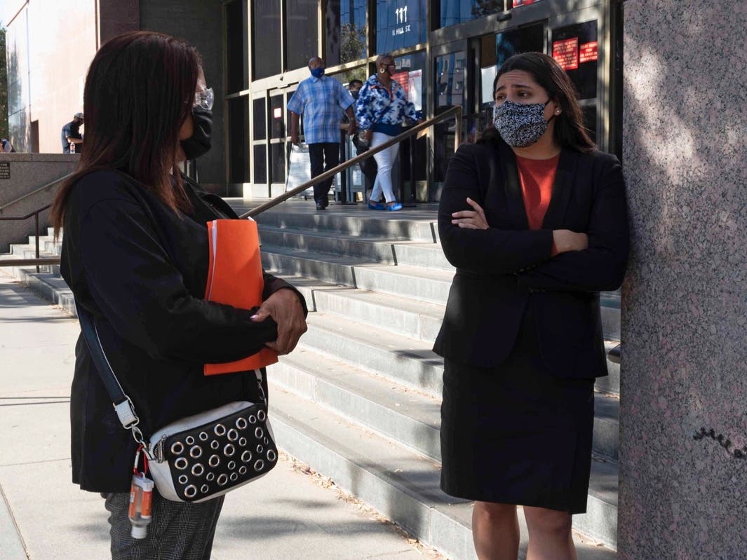 Attorney Nathaly Medina, at right, speaks with her client, Lynn Byers, before a hearing at the courthouse in downtown Los Angeles on Dec. 2, 2020. Medina is among a growing number of attorneys protesting mandatory court appearances.
