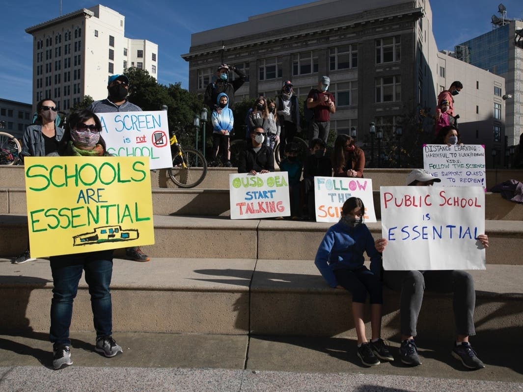 Kristin Bailey, right, a demonstration organizer, carries a sign in favor of giving parents the option of in-person instruction for their children during a rally in favor of reopening Brentwood schools on Sept. 15, 2020.