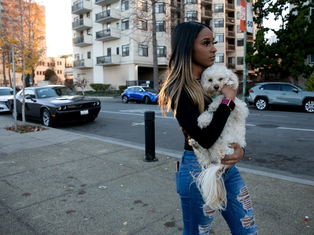 Jhonae Mazique carries her dog, Simba, to her friend’s apartment where she’s currently staying after losing her housing earlier this year, in Oakland on Dec. 8, 2020.