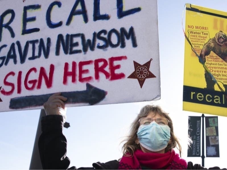 Recall Newsom volunteer Pat Miller holds up a sign during petition-signing event at SaveMart in Sacramento on Jan. 5, 2021.
