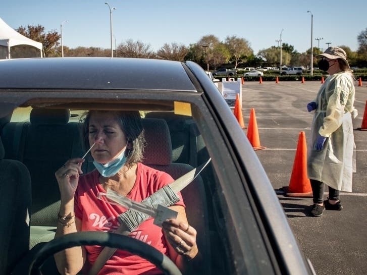 Diane Ahern swabs herself for COVID-19 at a testing site at the Long Beach Airport in Long Beach on Jan. 11, 2022. “I need to get tested every three days to be able to visit my parents at their retirement home,” Ahern said. “I’m nervous.” 