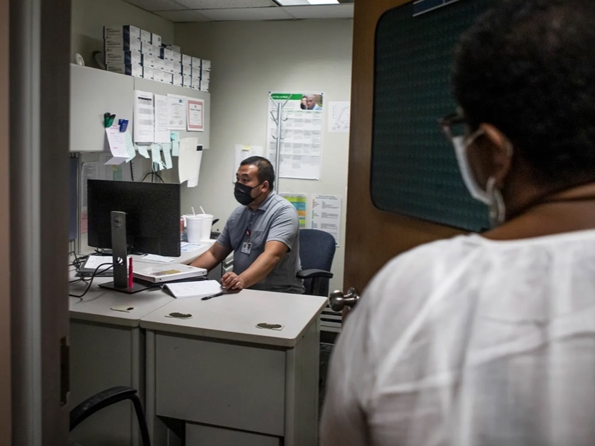 STD Investigator Hou Vang (left) works in his office as Jena Adams (right), Communicable Disease Program manager, checks in on him on June 8, 2022. 