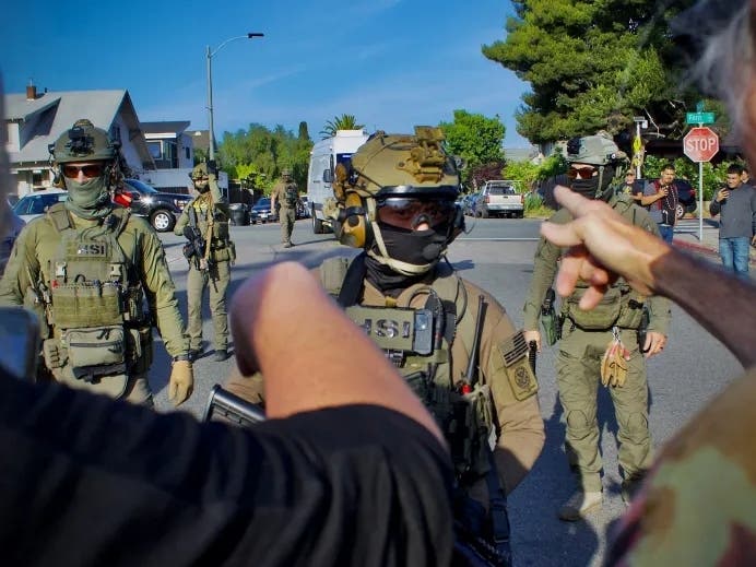 Neighbors confront Immigration and Customs Enforcement’s Special Response Team officers following an immigration raid at the Italian restaurant Buono Forchetta in San Diego on May 30, 2025. 