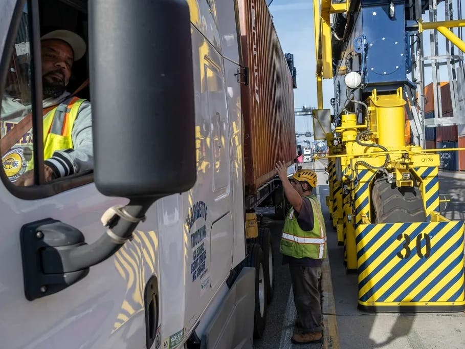 A hydrogen-powered, rubber-tired gantry crane loads a shipping container onto a semi-truck at Yusen Terminals at the Port of Los Angeles in San Pedro on Feb. 11, 2025.