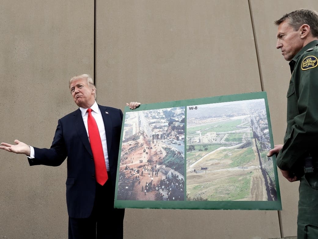 In this March 13, 2018, file photo, President Donald Trump holds a poster with photographs of the U.S. - Mexico border.