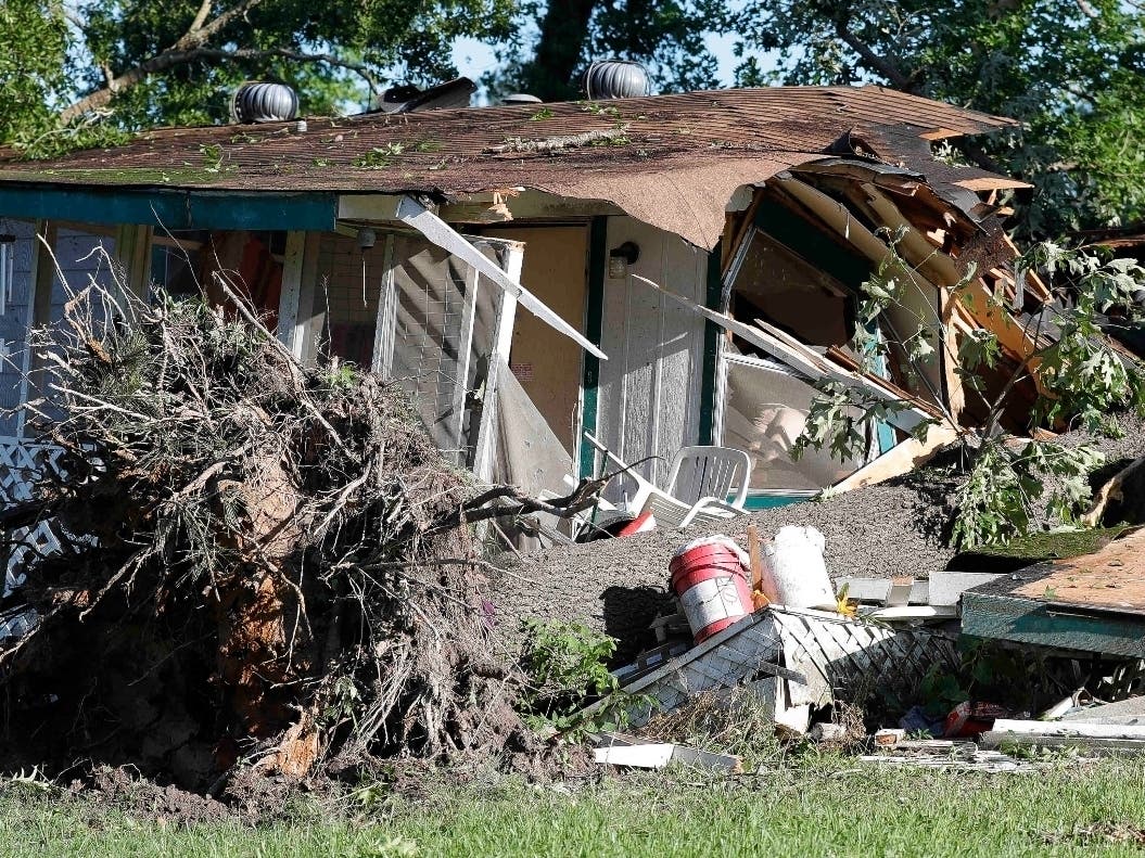A large tree is uprooted in front of a destroyed home, in Onalaska, Texas, after a tornado came through the night before.