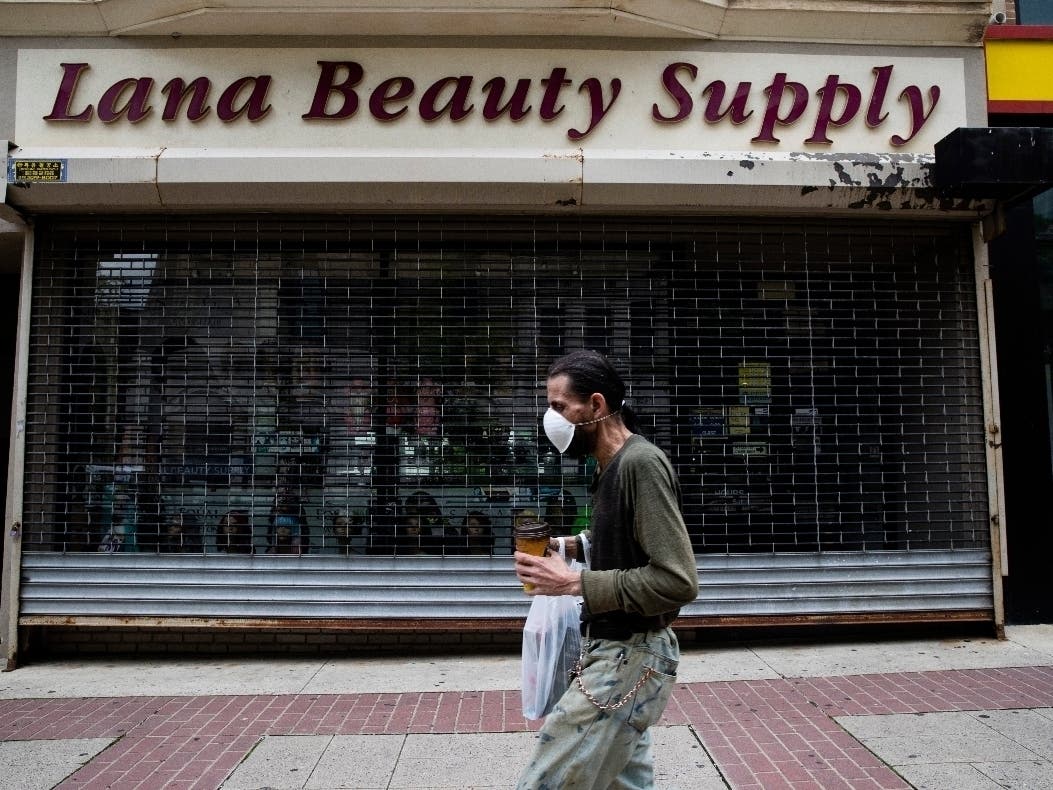 A shopper in a mask walks in front of a shuttered store in downtown Allentown, Pennsylvania.