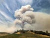 In this Aug. 18, 2020, file photo, a plume rises over a vineyard in unincorporated Napa County, Calif., as the Hennessey Fire burns. 