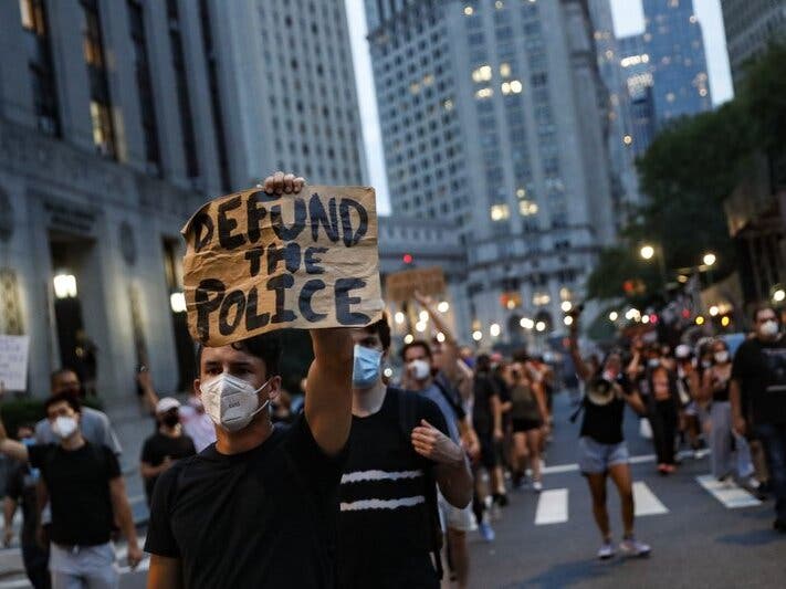 A demonstrator holds a sign that reads "Defund the Police" during a protest march in support of the Black Lives Matter movement and other groups, in New York.