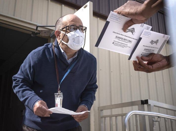 An employee of the Philadelphia Commissioners Office examines ballots at a satellite election office at Overbrook High School in Philadelphia.