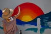 An artist painting a sunset landscape — perfect for the beach festival.