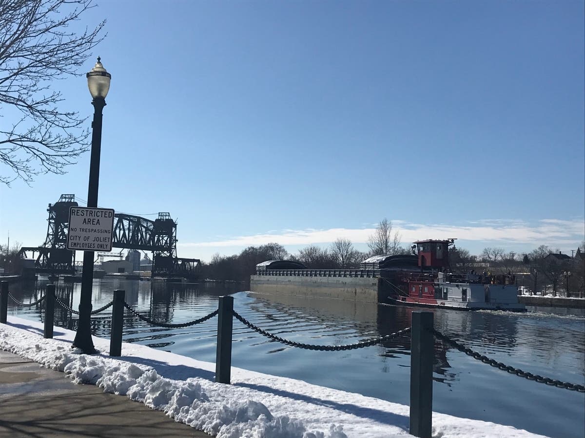 A barge passes through downtown Joliet on Wednesday morning. It's been nearly three weeks since a man jumped into the water near the Bicentennial Park. 