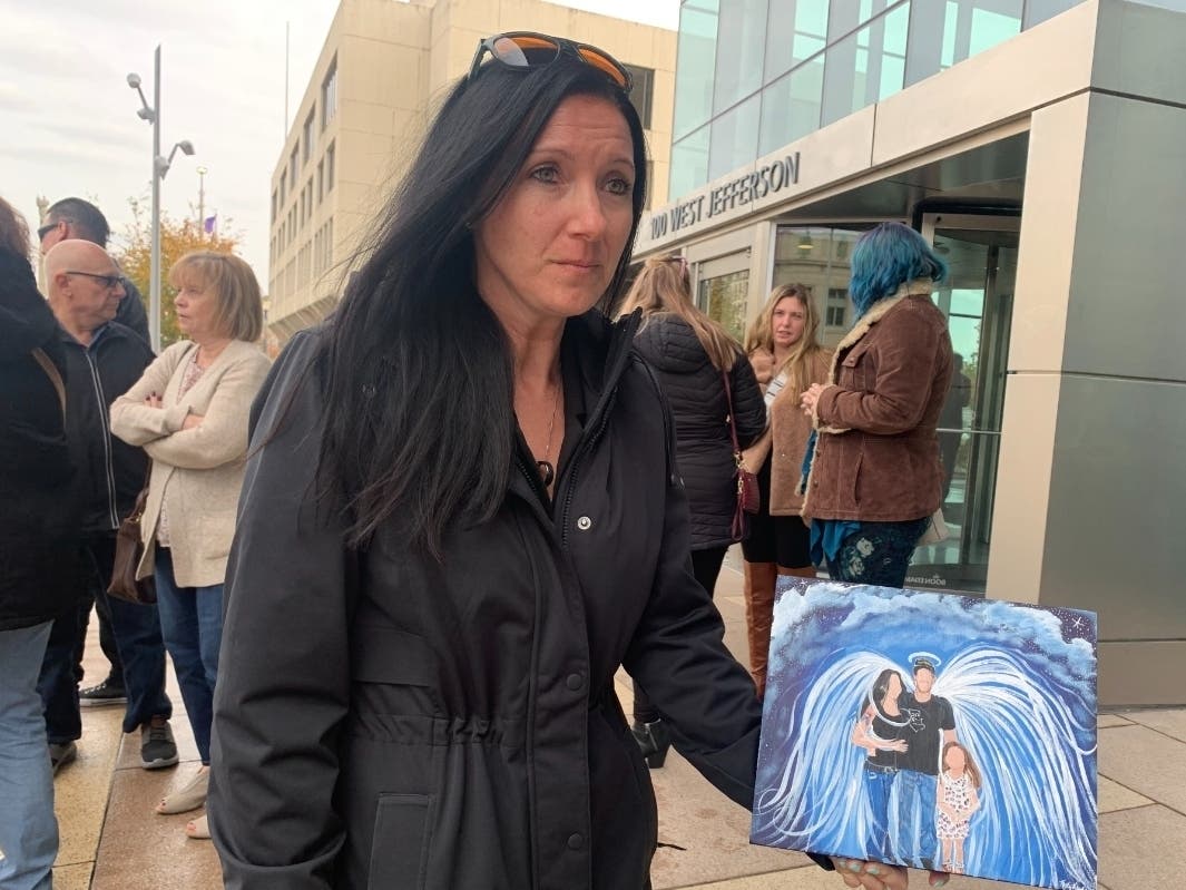 Carly Ercolini holds a painting that was done showing her late husband, Nick, in heaven, along with her and their now 9-year-old daughter, Ryan. 