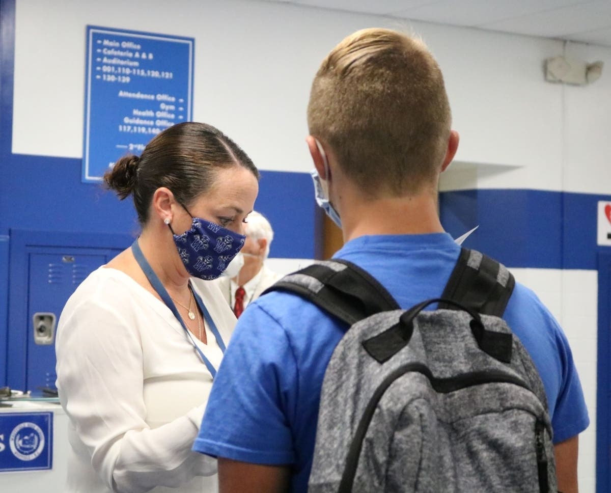 Westfield High School principal Mary Asfendis welcomes students back for in-person instruction on Sept. 10, as she checks to make sure student health questionnaires have been completed.