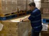 Ryan Beaman, the director of food resource management for All Faiths Food Bank, checks the inventory of emergency meal boxes