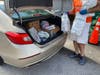 An All Faiths Food Bank volunteer loads food into a car during a mobile pantry in DeSoto County