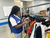 Youth Summer Employment Program participant Kaleiyah organizes a rack of clothes before it is brought out to the sales floor