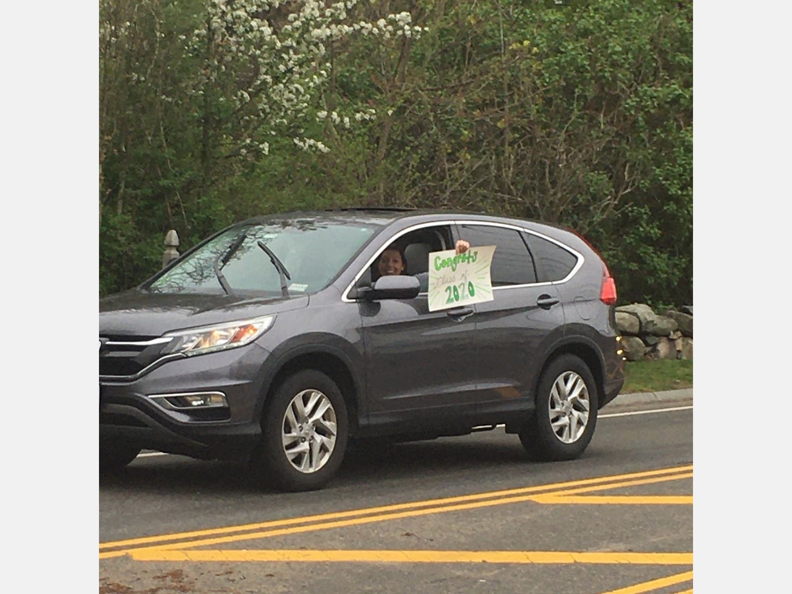 A gray car with a posterboard sign celebrating WHS' graduates.