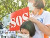 A little girl asks for help from the international community as she holds a sign that reads “Please Help Us!” in front of the enforcement agency in Miao-Li, Taiwan on August 21, 2020