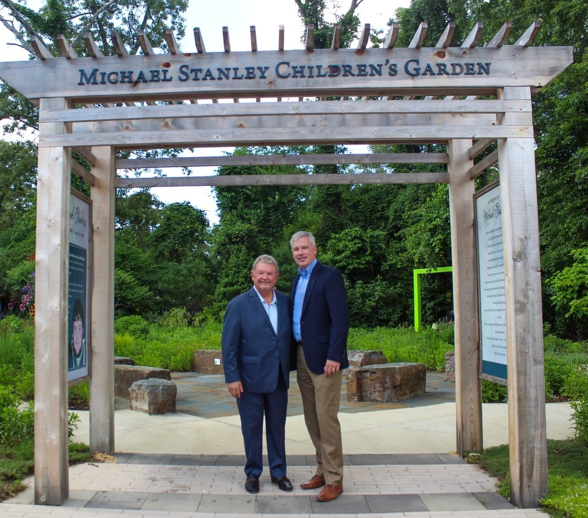 Ken Stanley, left, stands with Michael Brady, CEO Hospice of the Chesapeake, right, at the entrance of the Michael Stanley Children’s Garden, which was officially dedicated to the memory of Stanley’s son on June 4 in Pasadena, Maryland