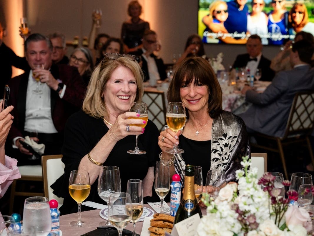 Patti McMillan, left, joins Harriet Manis Adam in raising a cold glass of Stella Artois, her husband Brian Adam’s favorite beer, after viewing a video about his and his family’s experience as a palliative and hospice patient with Hospice of the Chesapeake