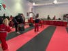 The Dojo Crabapple Chief Instructor Chris Walker demonstrates a proper chamber and pivot for a round kick to students in the afterschool program. The pink belt he is wearing is National Breast Cancer Awareness Month
