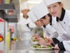 Happy chef looking up from preparing salad in culinary class