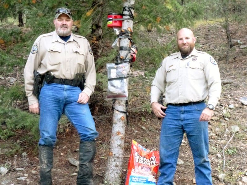 Colorado Parks and Wildife officers Bob Carochi, left, and Zach Holder stand next to a tree that was baited with salmon fillets, honey and dog food by a poacher trying to attract bears on Table Mountain in remote Fremont County.