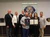Officials of the Orland Fire Protection DIstrict and members of the Roche family displaying the plaque that will be placed in the Board room