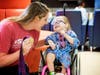Missy Franklin shows her Olympic medals to a child undergoing cancer treatment. Missy works with Swim Across America to help raise funds for cancer research.