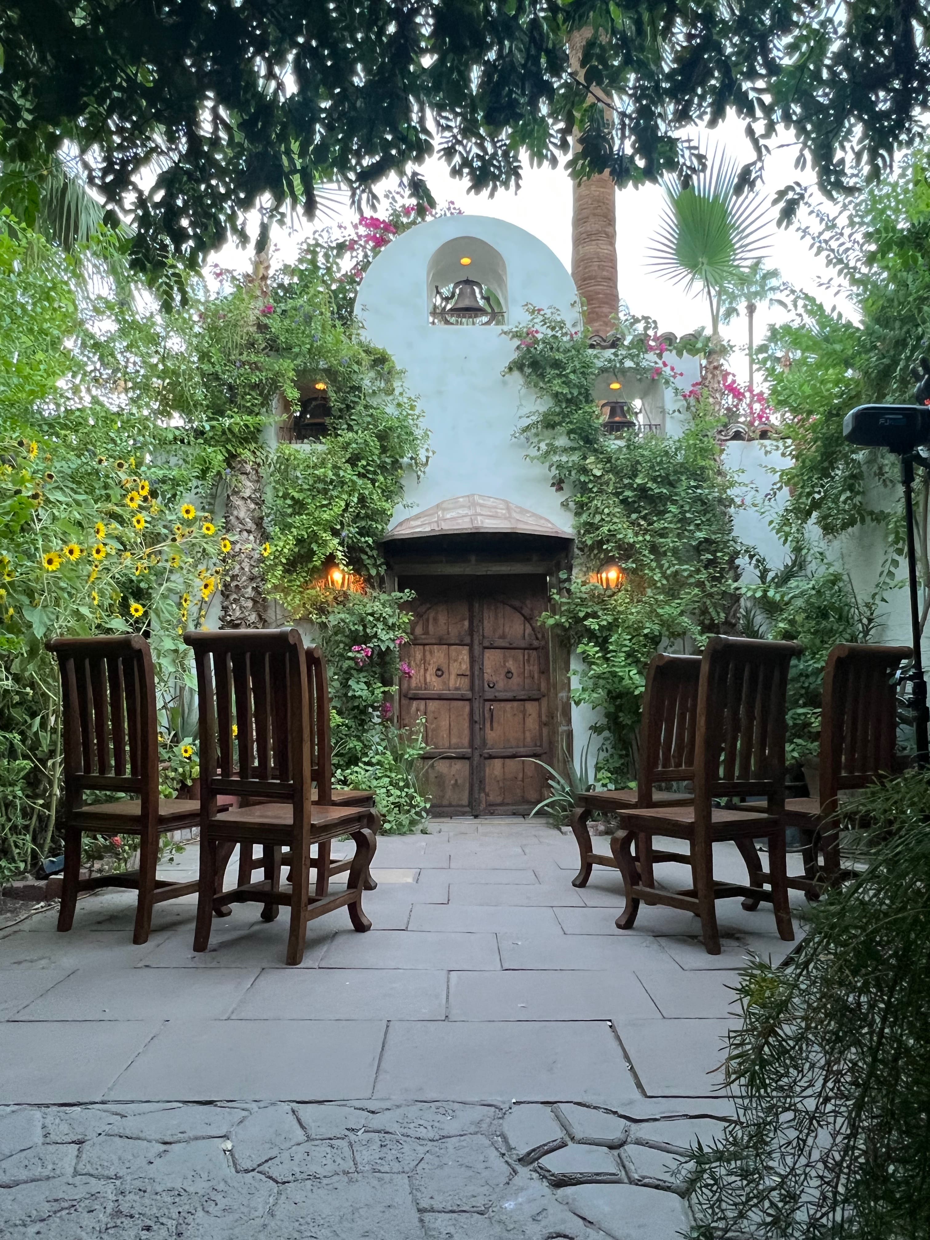 spanish bell tower with patio, chairs and climbing vines