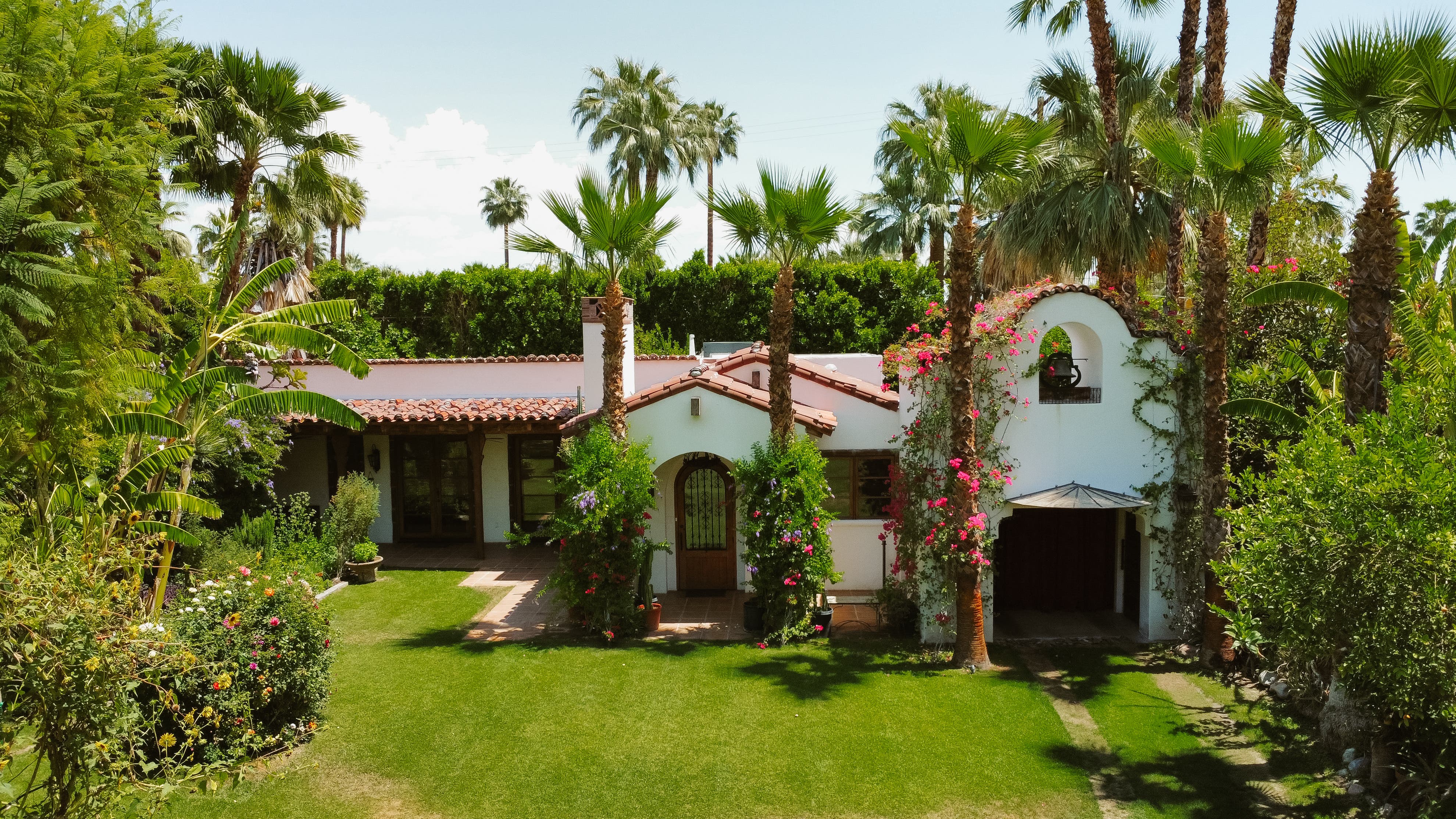 spanish mediterranean building with bell tower surrounded by palm trees and green yard