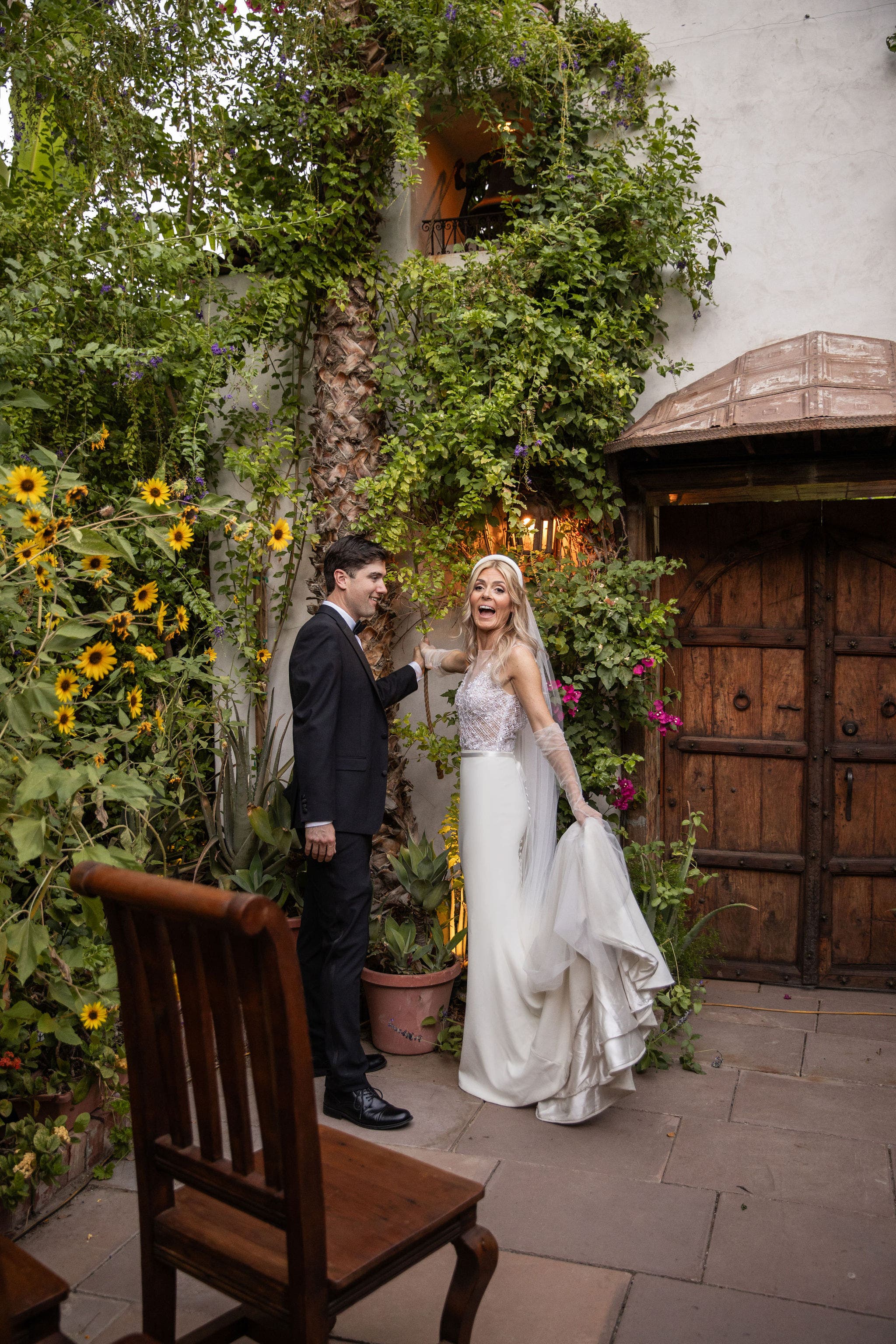 bride and groom pulling a rope to ring a bell I front of wood spanish doors