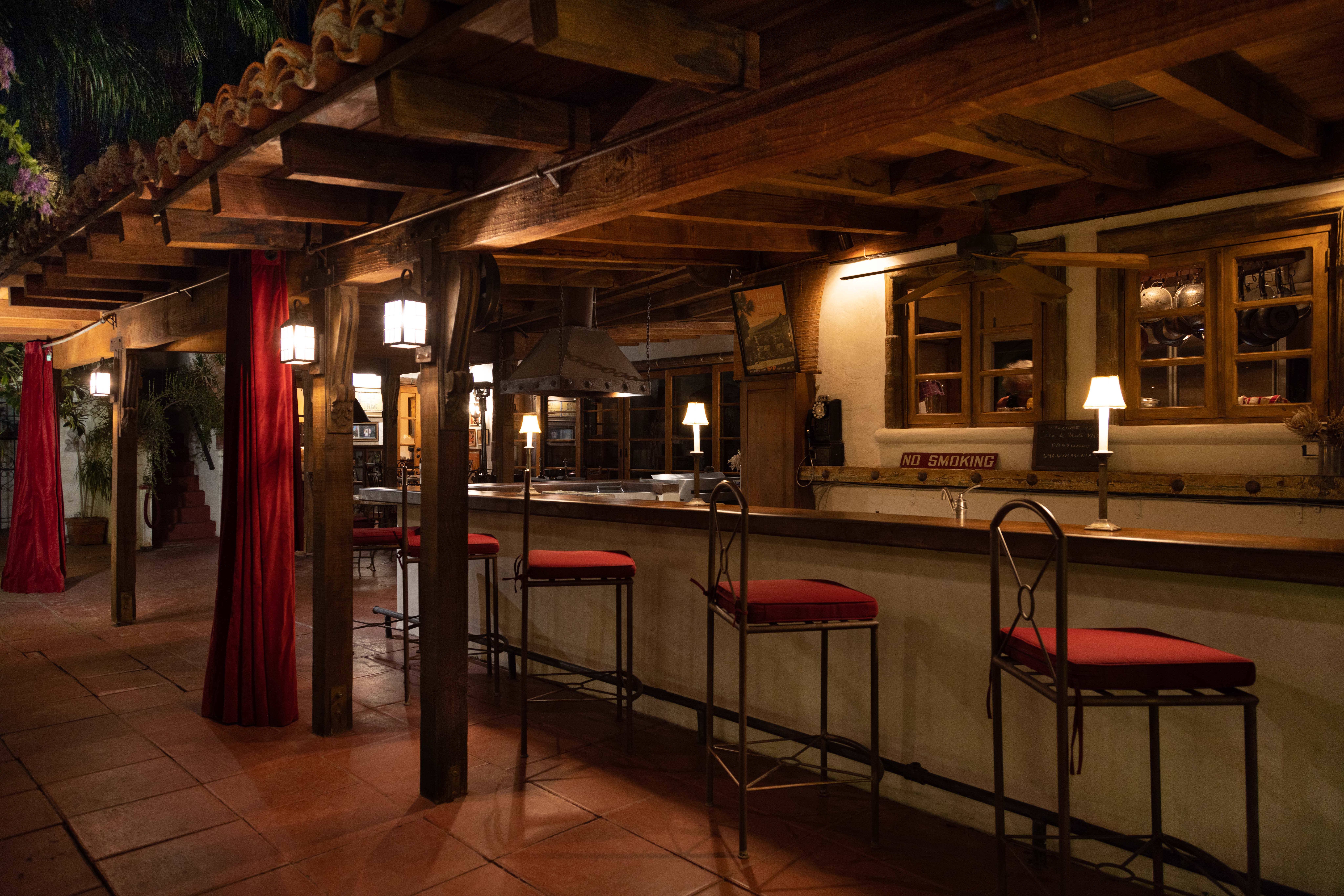 outdoor bar with tall chairs, red cushions at night