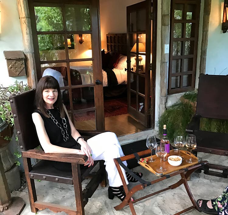 woman dressed in black and white enjoying wine on a patio in front of an open door to vacation rental in Palm Springs